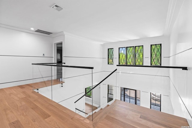 stairs with wood-type flooring, ornamental molding, and a fireplace