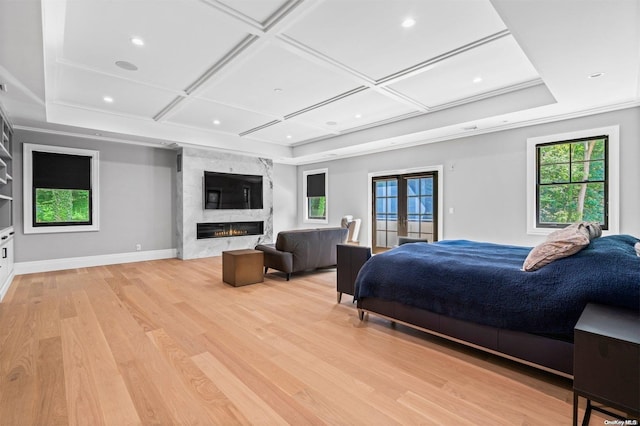 bedroom with french doors, light wood-type flooring, coffered ceiling, and a premium fireplace