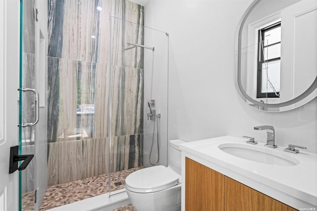 bathroom with a shower with door, vanity, and toilet