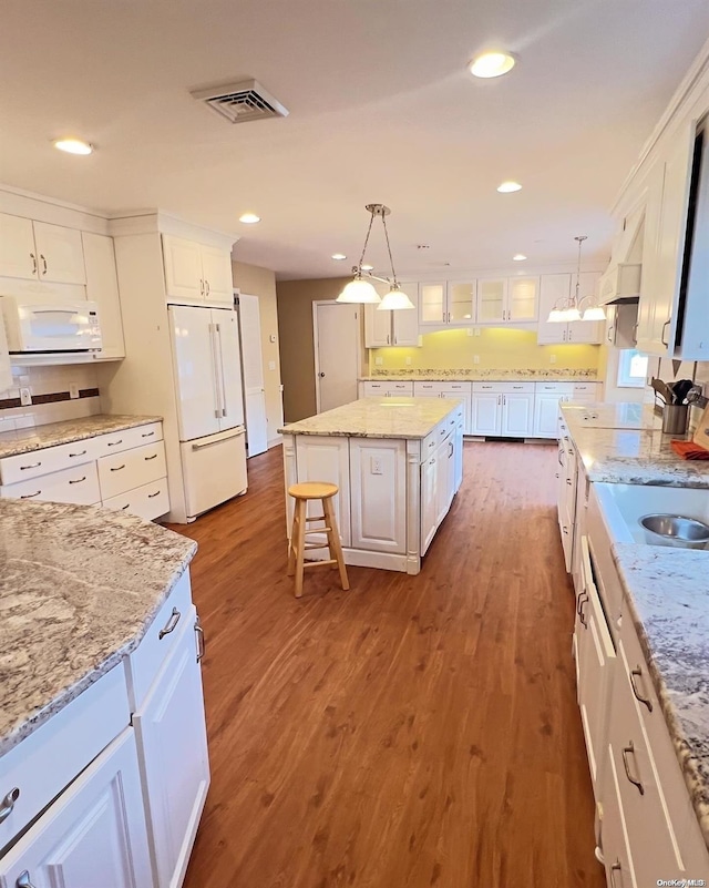 kitchen featuring pendant lighting, white appliances, white cabinets, a kitchen island, and dark hardwood / wood-style flooring