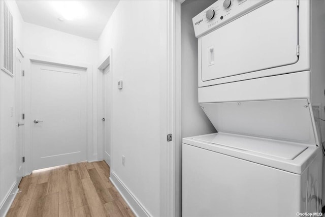 laundry area with light hardwood / wood-style floors and stacked washer / drying machine