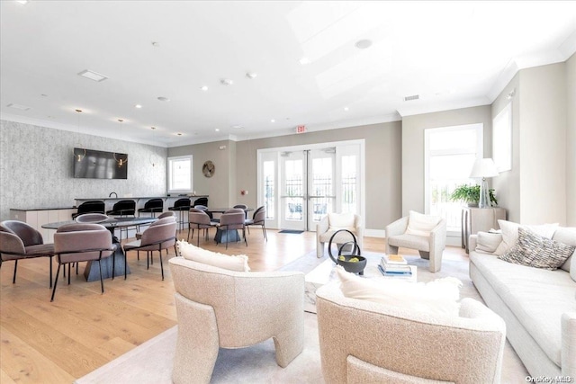 living room featuring light hardwood / wood-style floors, ornamental molding, and french doors