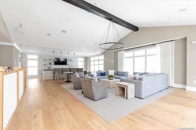 living room with a notable chandelier, vaulted ceiling with beams, light hardwood / wood-style floors, and a wealth of natural light