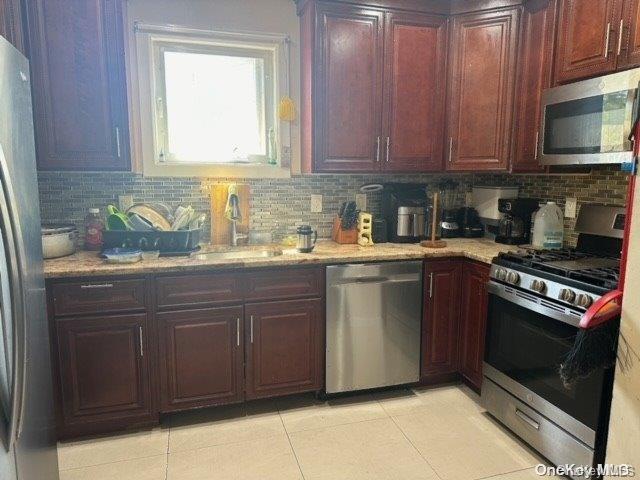 kitchen with light tile patterned floors, stainless steel appliances, tasteful backsplash, and sink