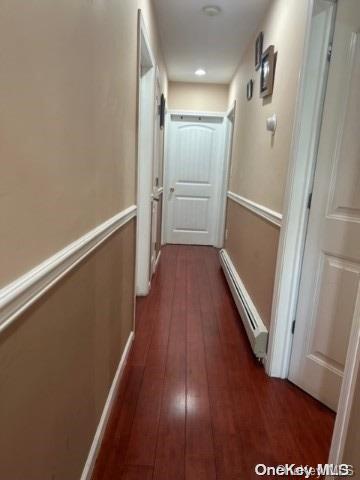 hallway with dark hardwood / wood-style floors and a baseboard heating unit