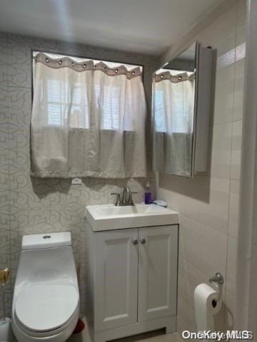 bathroom featuring a shower with curtain, vanity, toilet, and tile walls