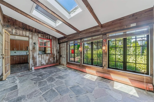 unfurnished sunroom featuring vaulted ceiling with skylight and a baseboard radiator