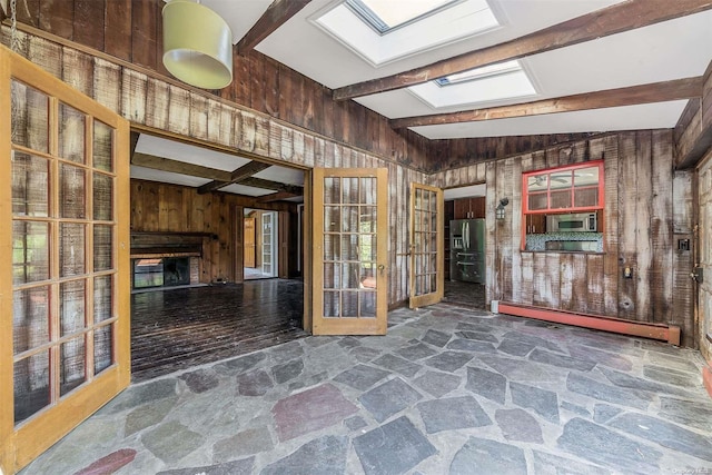 interior space featuring baseboard heating, a skylight, wood walls, and beamed ceiling