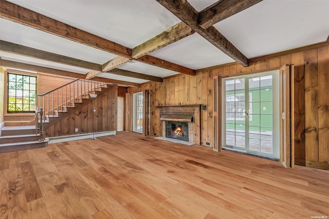 unfurnished living room featuring wood walls, light hardwood / wood-style floors, beamed ceiling, and a baseboard heating unit