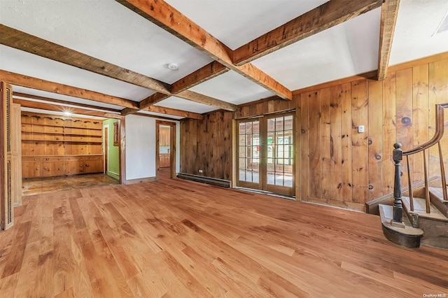 unfurnished living room featuring french doors, beamed ceiling, a baseboard heating unit, wood-type flooring, and wooden walls