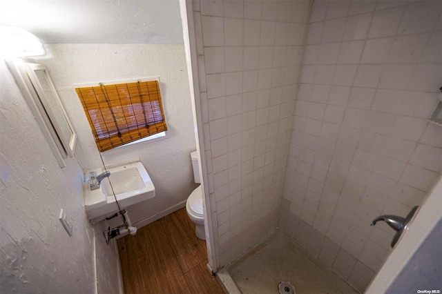 bathroom with a tile shower, sink, toilet, and hardwood / wood-style flooring