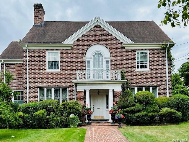 view of front facade with a front yard and a balcony