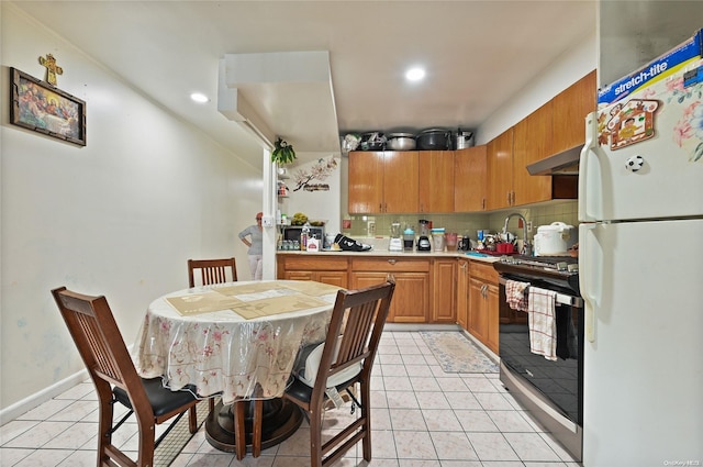 kitchen with black electric range oven, white refrigerator, sink, tasteful backsplash, and light tile patterned flooring