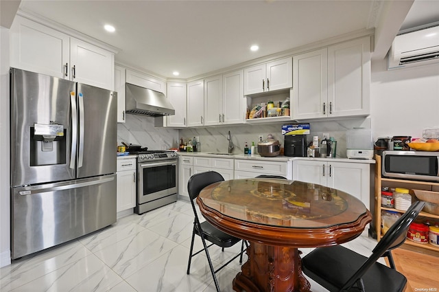 kitchen featuring white cabinets, appliances with stainless steel finishes, a wall unit AC, and wall chimney range hood