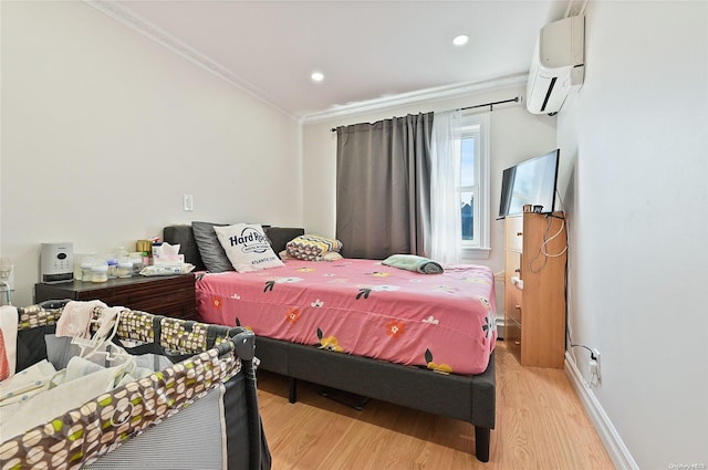 bedroom with a wall mounted air conditioner, light wood-type flooring, and crown molding