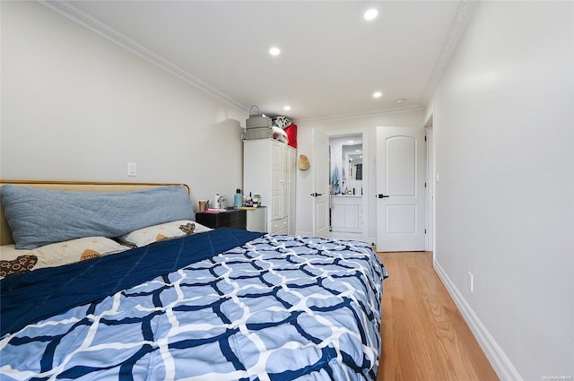 bedroom with hardwood / wood-style flooring, ornamental molding, and ensuite bath