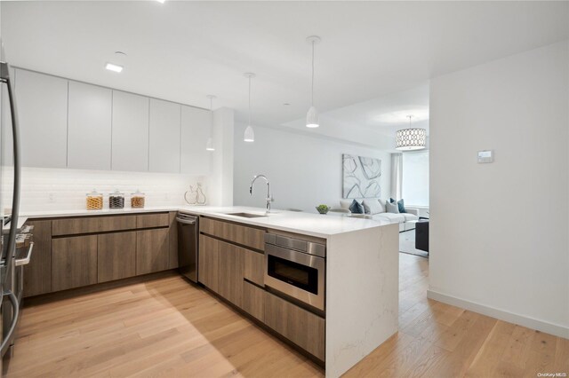 kitchen with kitchen peninsula, white cabinets, hanging light fixtures, and light wood-type flooring