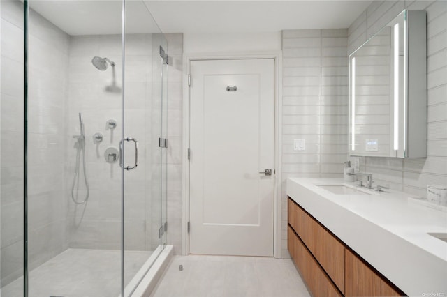 bathroom with vanity, a shower with shower door, tile walls, and tasteful backsplash