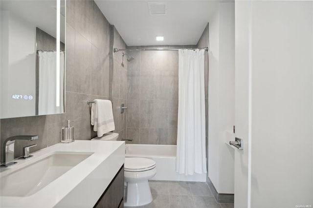 full bathroom featuring shower / bath combination with curtain, tile patterned floors, vanity, tile walls, and toilet