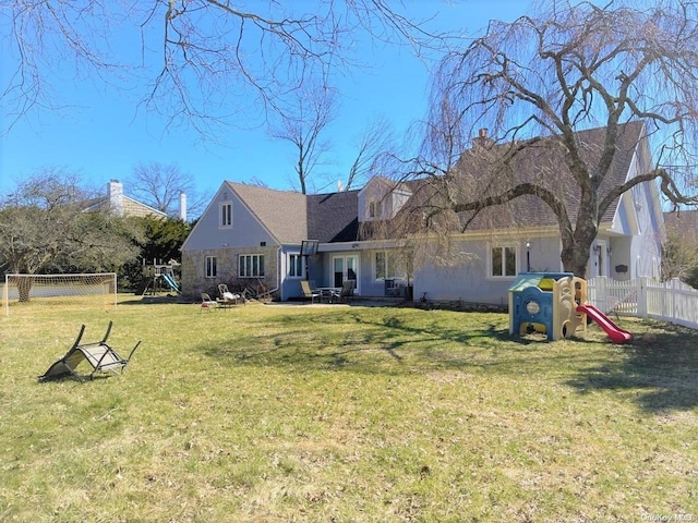 rear view of property with a yard and a playground