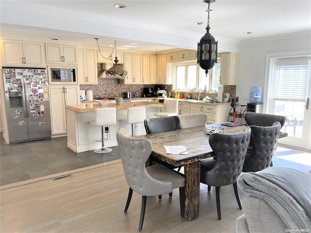 dining area with plenty of natural light, sink, wood-type flooring, and ornamental molding