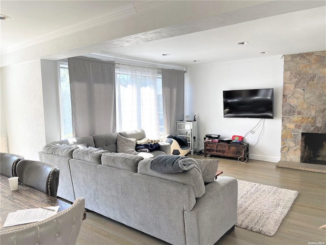 living room featuring a stone fireplace, crown molding, and hardwood / wood-style floors