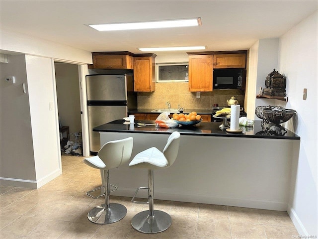 kitchen with decorative backsplash, stainless steel fridge, and a kitchen bar