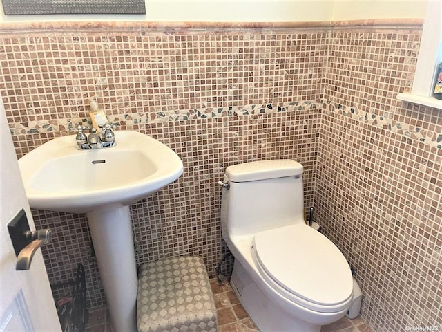 bathroom featuring toilet and tile walls