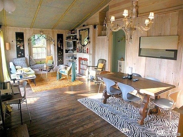 dining space featuring hardwood / wood-style flooring, wood walls, and lofted ceiling