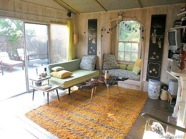 living room featuring a wealth of natural light, wood walls, and vaulted ceiling