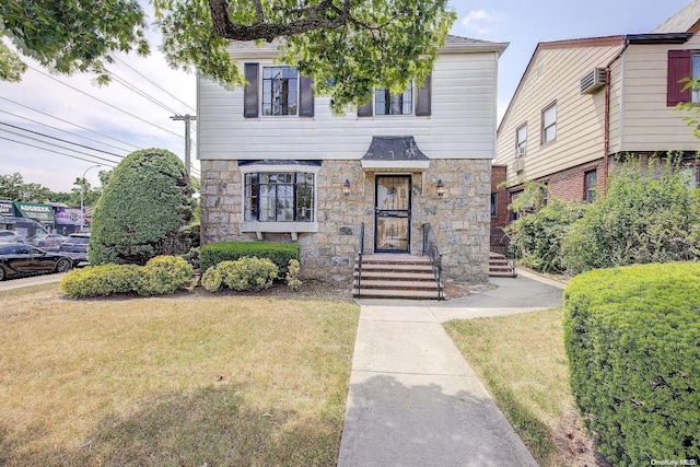 view of front of property featuring a wall unit AC and a front lawn