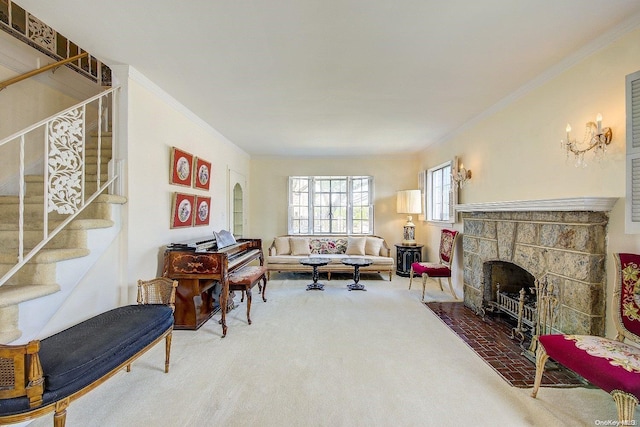 living room with a stone fireplace, crown molding, and carpet