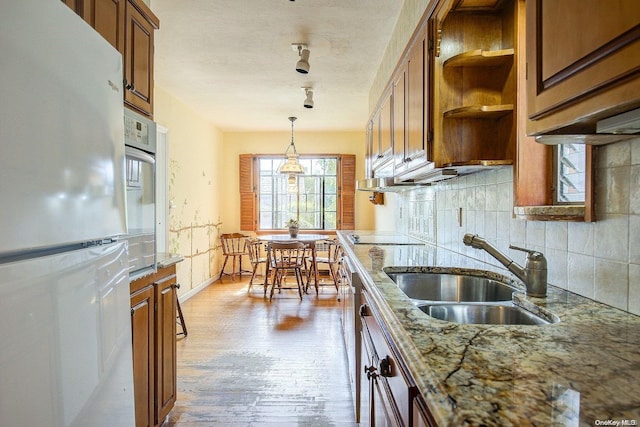 kitchen featuring sink, hanging light fixtures, light hardwood / wood-style floors, white fridge, and light stone counters