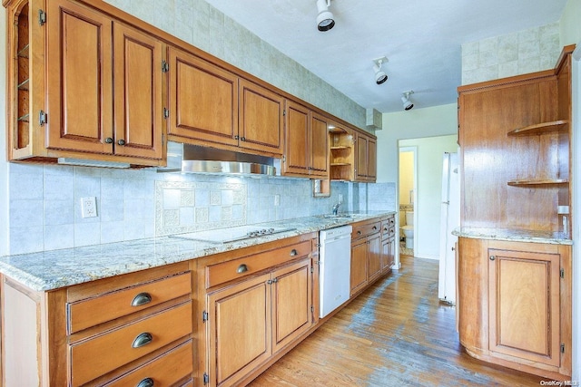 kitchen with dishwasher, sink, light wood-type flooring, light stone counters, and cooktop