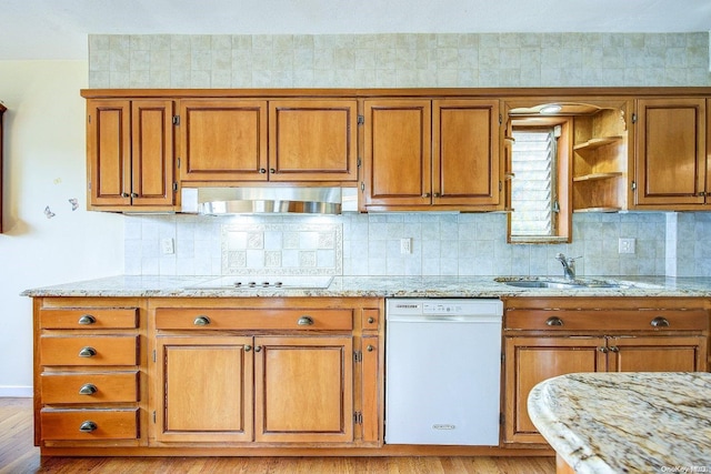 kitchen with white dishwasher, light hardwood / wood-style floors, tasteful backsplash, stovetop, and light stone counters