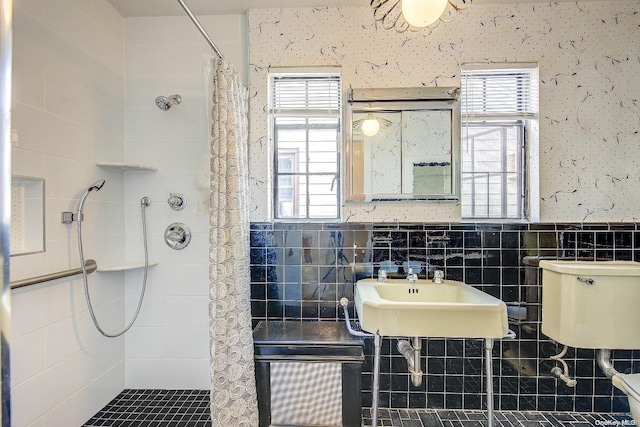 bathroom featuring sink, a tile shower, tile walls, and a wealth of natural light