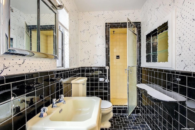 bathroom featuring toilet, tile patterned floors, tile walls, and sink