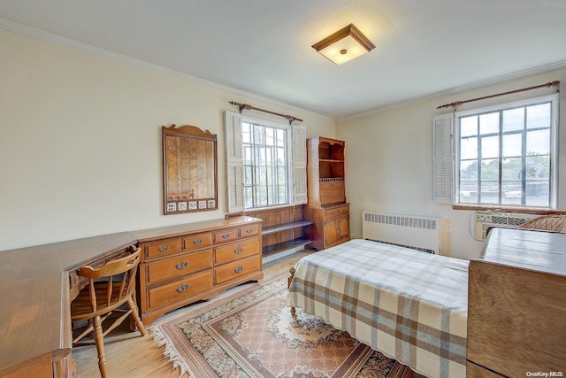 bedroom featuring multiple windows, radiator heating unit, ornamental molding, and light hardwood / wood-style flooring