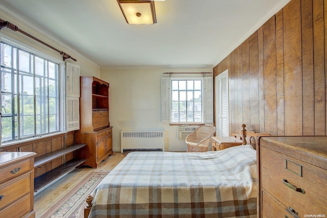 bedroom with light hardwood / wood-style floors, crown molding, radiator, and multiple windows