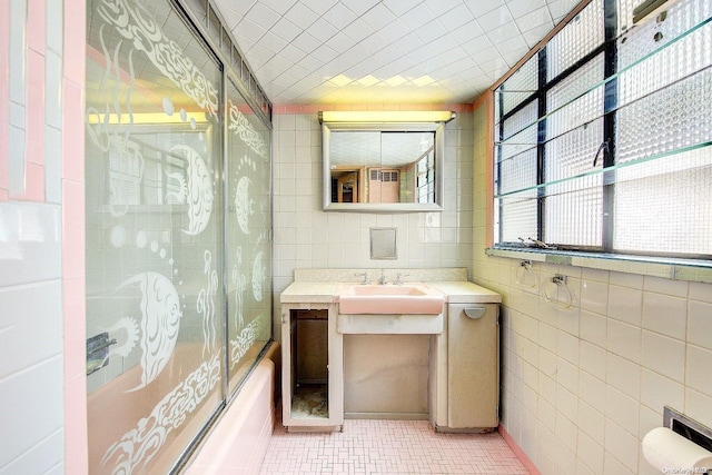 bathroom with tile patterned flooring, vanity, shower / bath combination with glass door, and tile walls