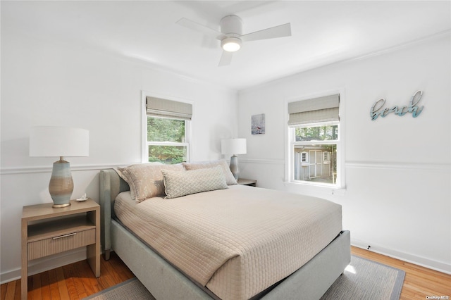 bedroom with ceiling fan, wood-type flooring, and multiple windows