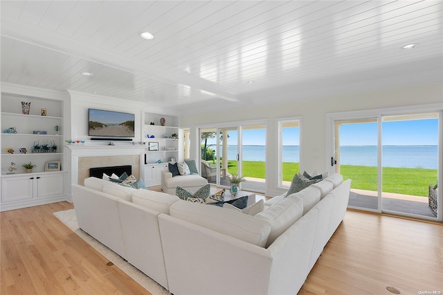 living room with a tile fireplace, light hardwood / wood-style flooring, wood ceiling, and built in features