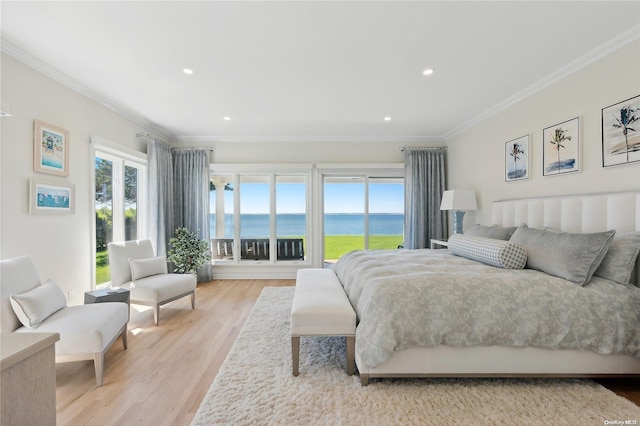 bedroom with a water view, light wood-type flooring, and multiple windows