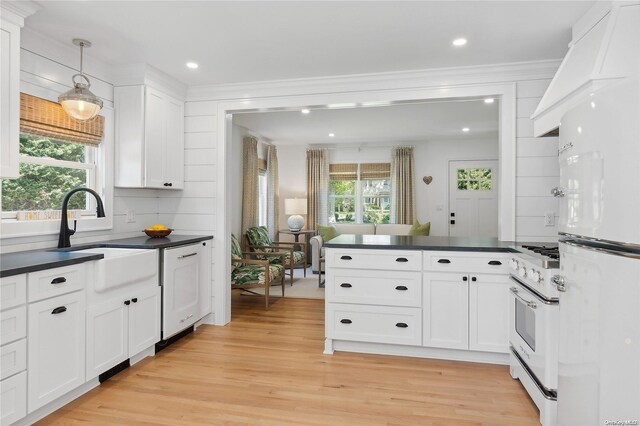 2100 Park Ave, Mattituck, NY 11952 - kitchen with freestanding refrigerator, range with gas cooktop, dark countertops, light wood-type flooring, and white cabinetry
