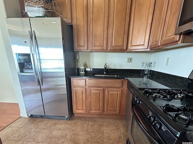 kitchen with sink, stainless steel appliances, and dark stone counters