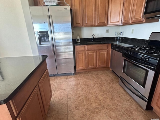 kitchen featuring dark stone counters, sink, and stainless steel appliances