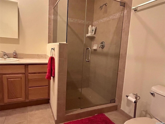 bathroom featuring tile patterned flooring, vanity, toilet, and walk in shower