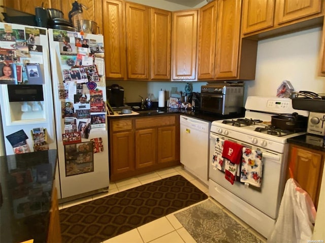 kitchen featuring light tile patterned flooring, white appliances, and sink