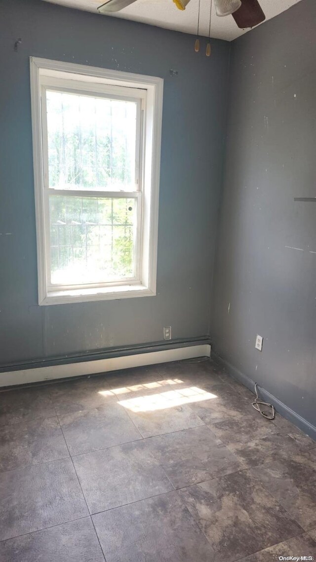 unfurnished room with ceiling fan and a baseboard heating unit