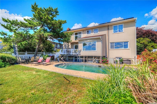 rear view of house featuring a patio area, a fenced in pool, and a yard